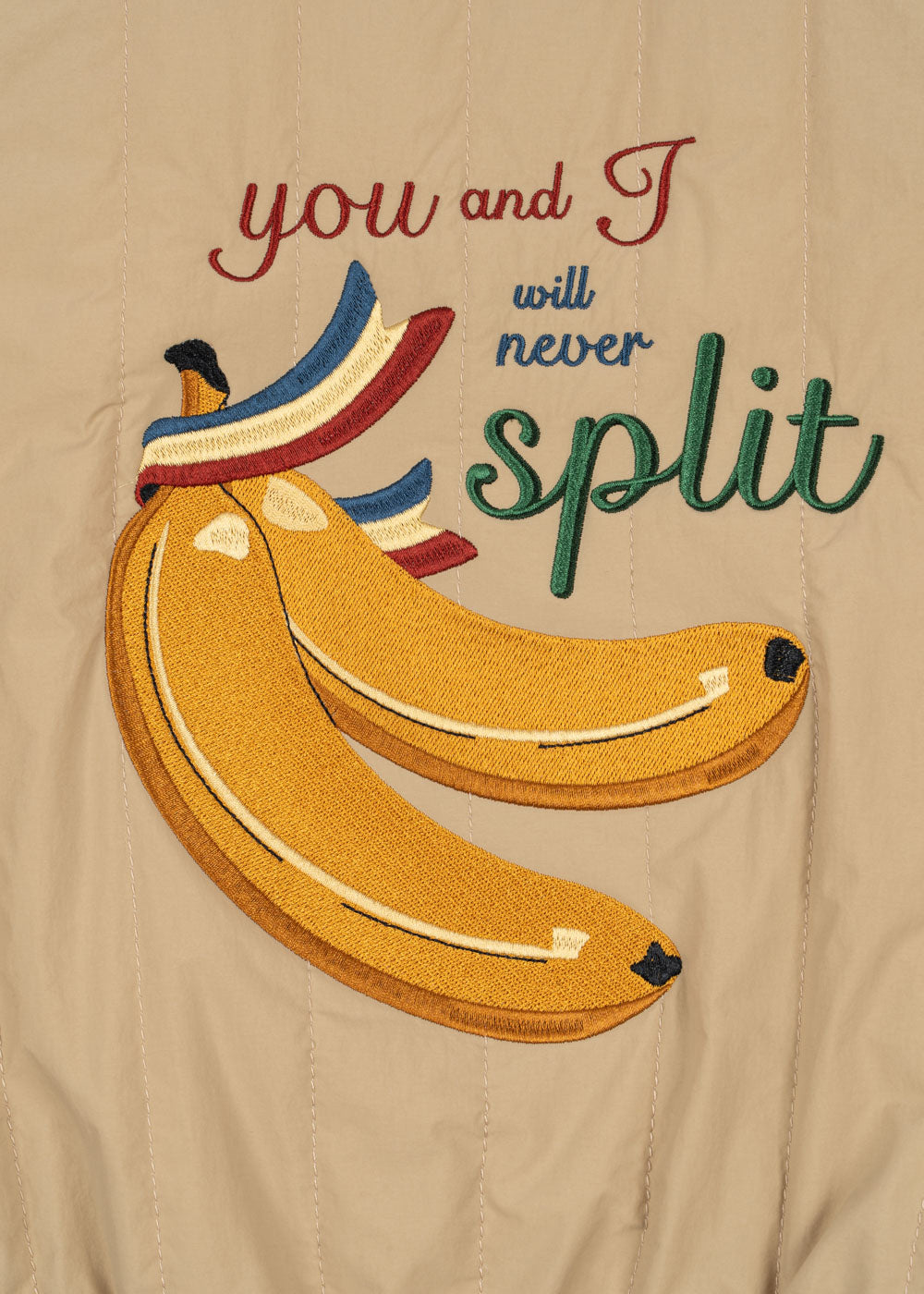 Embroidered design of bananas with text 'you and I will never split' on a beige background