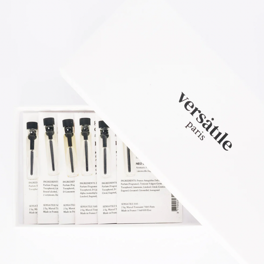 Image shows the contents of the discovery box and the image is of a white rectangular box with the logo Versatile Paris embossed on it. The box is opened to reveal a sample of each of the perfumes - the samples are in small glass vials with black stoppers and attached on white cards with black writing detailing the scent and ingredients of each fragrance