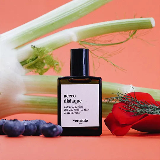 Perfume bottle labeled 'accro disiaque' by 'versèlute' on a colorful background with vegetables.
