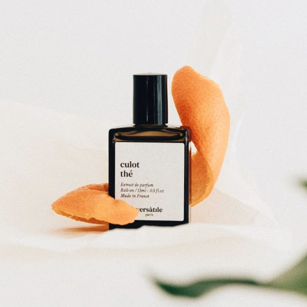 Perfume bottle labeled 'culot the' with orange peel on a light background