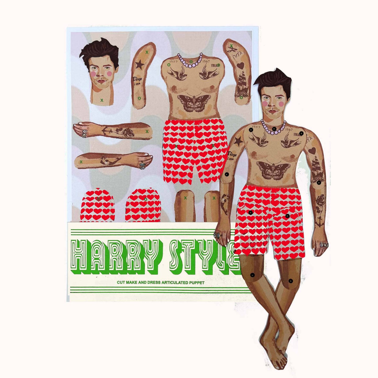 A packaged paper doll set with various outfits and accessory cutouts, featuring a style inspired by Harry Styles, with a prominent 'HARRY STYLES' text at the top.