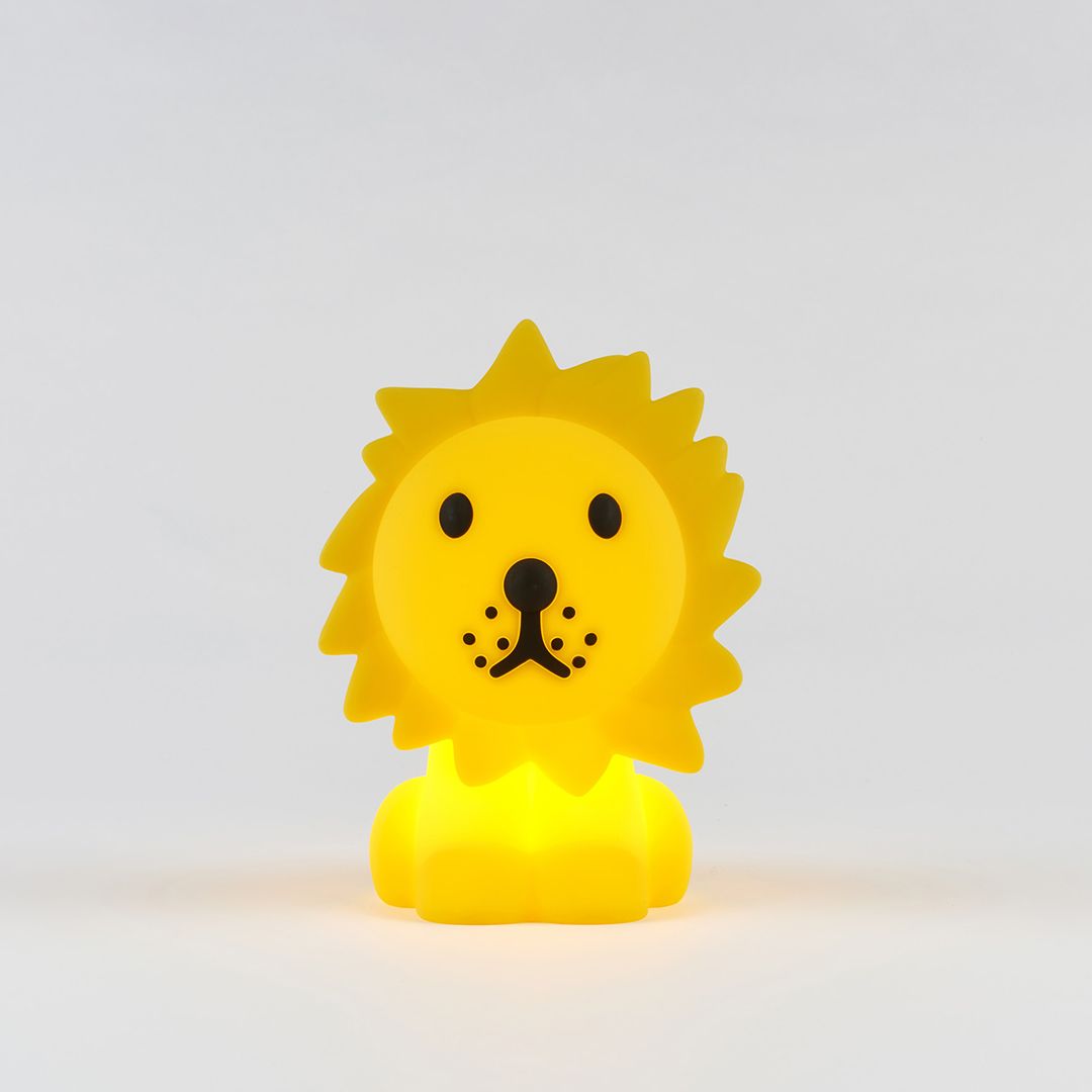 A yellow silicone lion-shaped nightlight illuminated with a gentle light, against a white background.