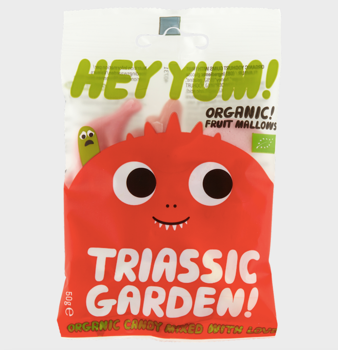 Packaging of HEY YUM! organic fruit marshmallows shaped like dinosaurs. The package is red with an illustration of a smiling marshmallow character and text 'TRIASSIC GARDEN'.