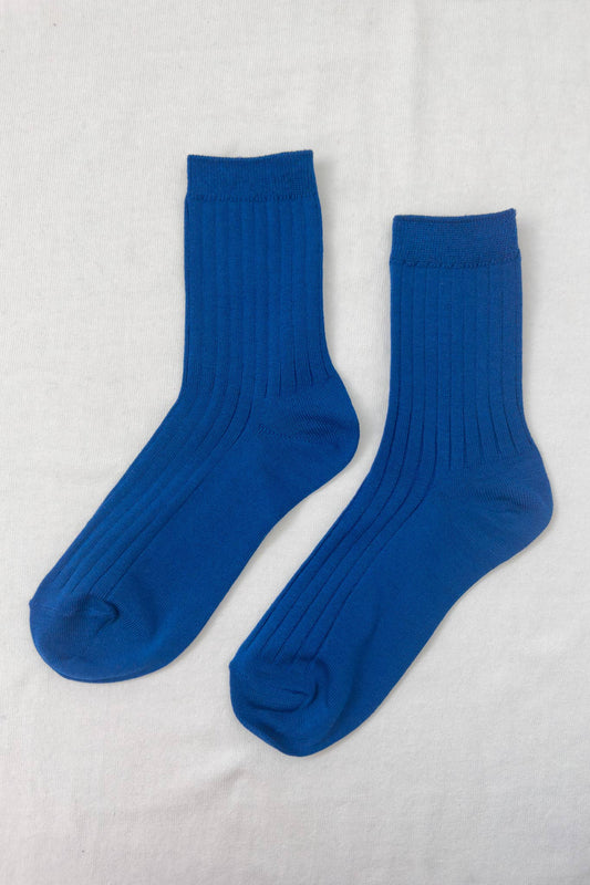 A pair of cobalt blue ribbed crew socks laid flat on a white background, showing their texture and design.