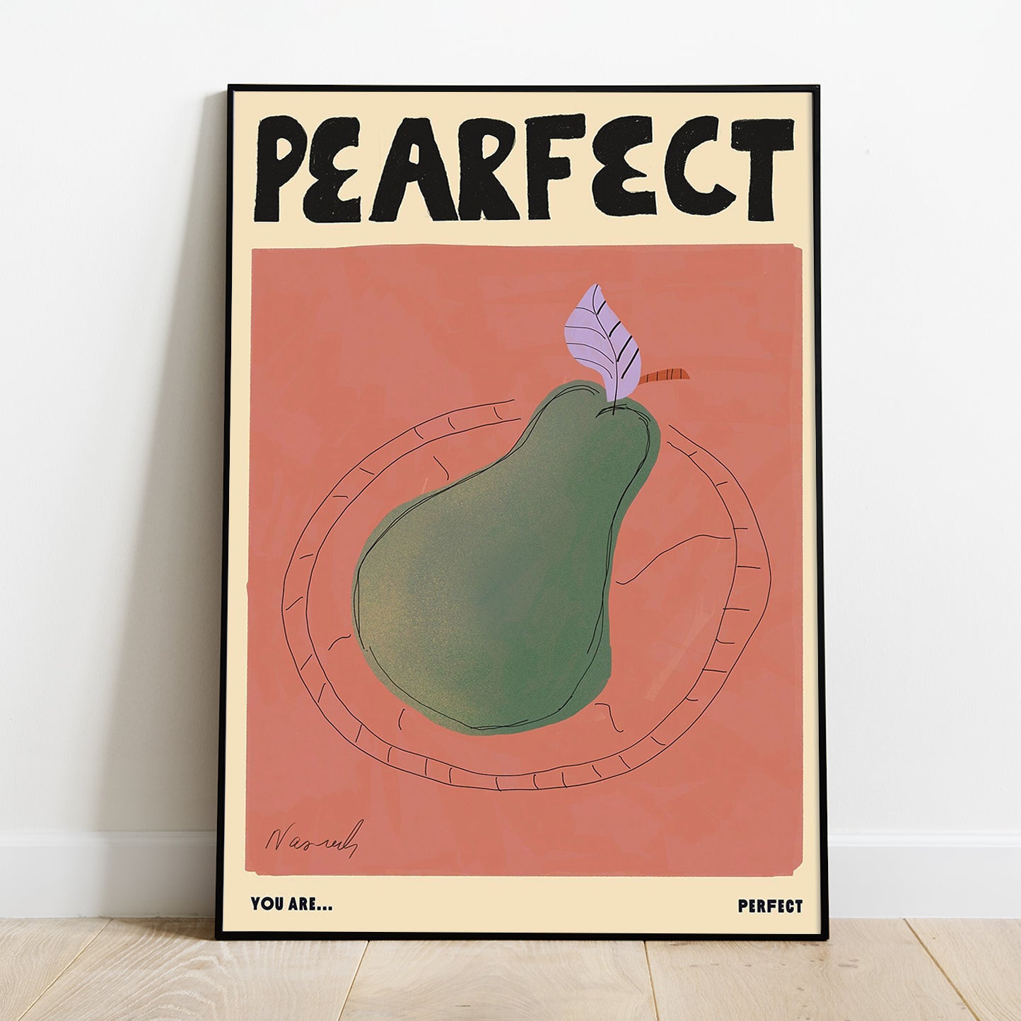 A Natalia Bagniewska Pearfect print. The background is peachy pink in colour. The pear is green in colour with the leaf being lilac. It is kept on a transparent plate. Beneath the pink background, in black, on the left hand side its says You Are... and on the right it says Perfect. The print is framed and kept against a white wall on wooden floor