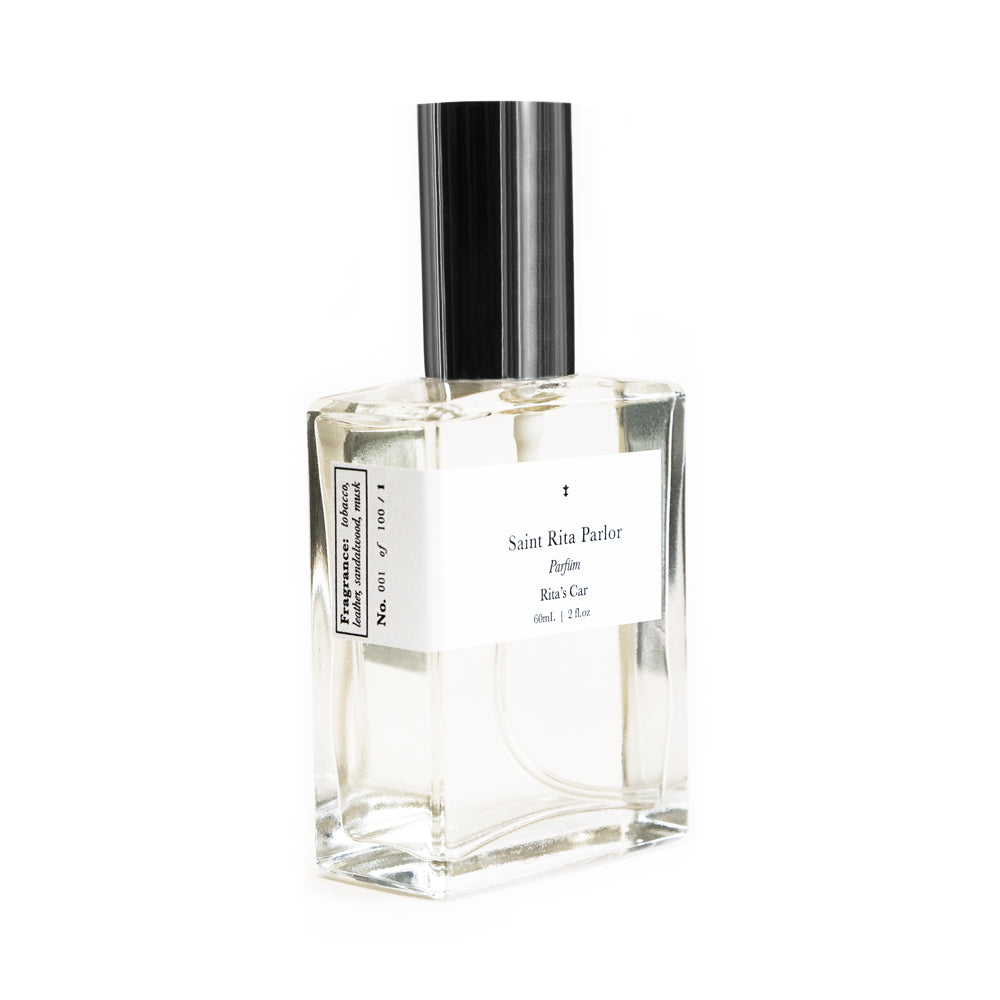 A clear glass bottle of Saint Rita Parlor perfume with a silver cap, labeled 'Rita's Car' with a volume of 60ml.