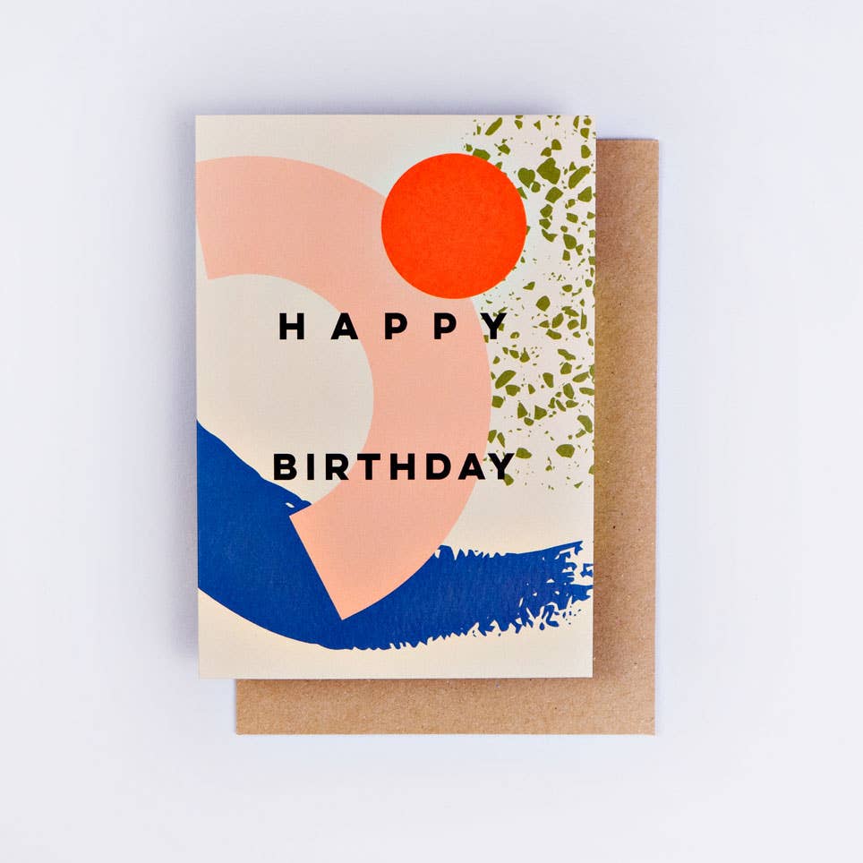A colorful birthday greeting card with abstract shapes and the text 'HAPPY BIRTHDAY' on the front, accompanied by a kraft envelope.