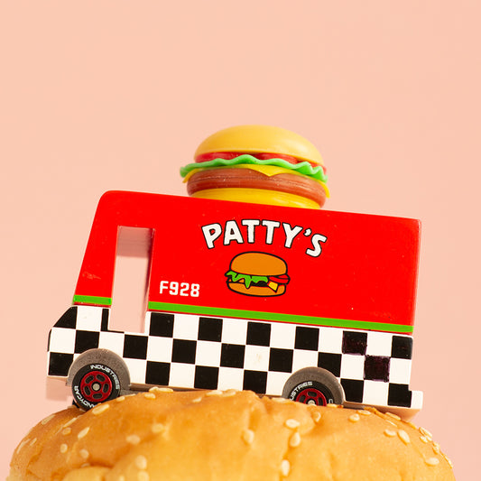 A toy hamburger van with a bun and fixings on top, predominantly red and yellow with a black and white checkered pattern on the sides, labeled 'PATTY'S F928'.