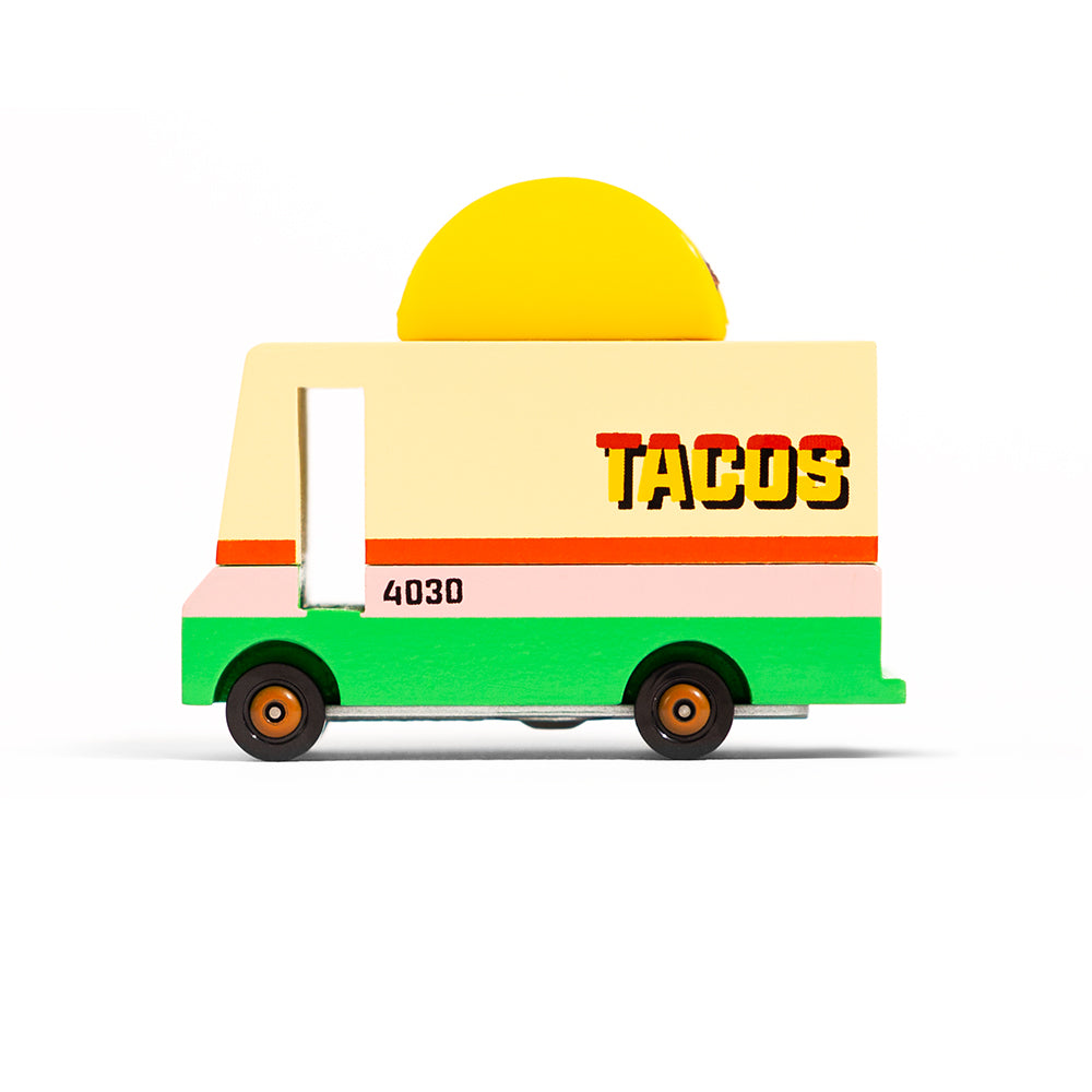 A wooden toy truck with a 'TACOS' sign on the side, featuring colorful decorations and a sun motif on the top.