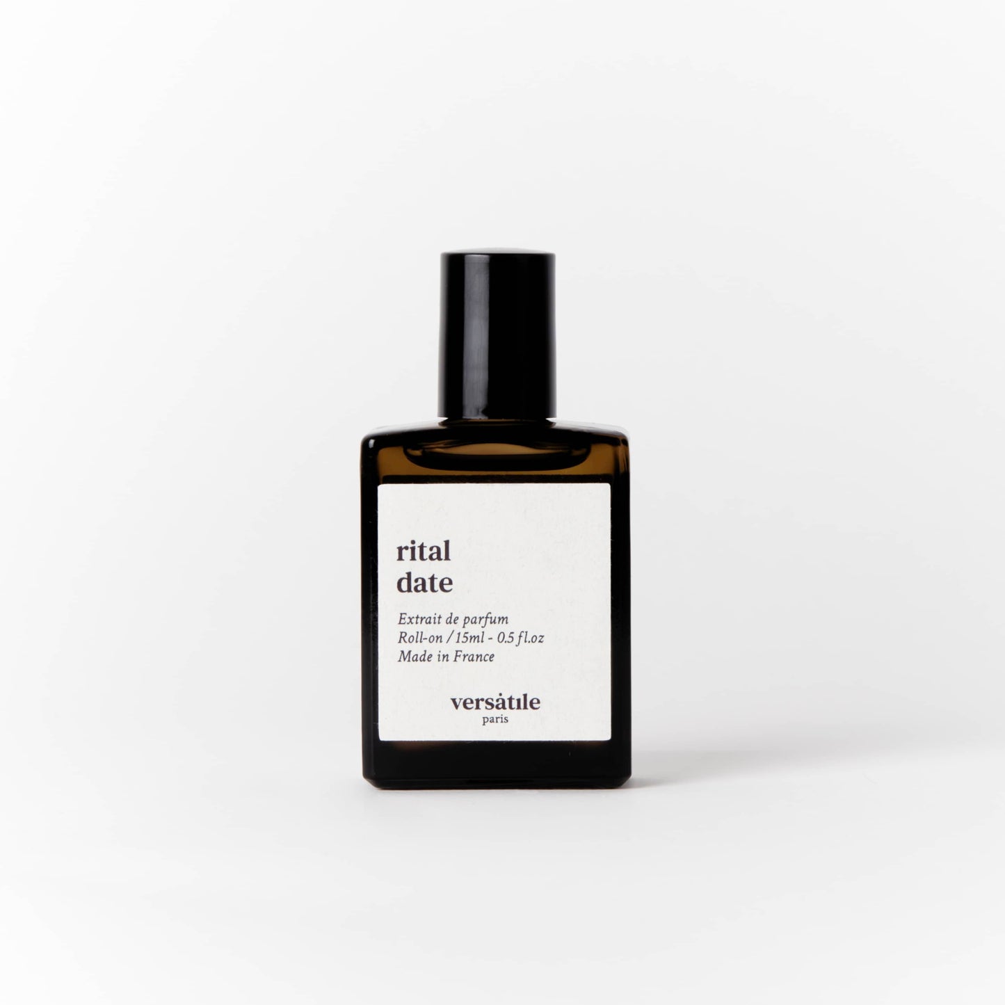 An image of a brown perfume bottle with a black screw on lid on it. The bottle has a square white label on it that says the scent of the perfume 'rital date' along with the amount of perfume in the bottle, that being 15ml and where the perfume was made, that being in France. Beneath this it says versatile Paris.