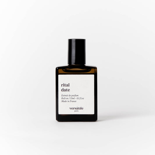 An image of a brown perfume bottle with a black screw on lid on it. The bottle has a square white label on it that says the scent of the perfume 'rital date' along with the amount of perfume in the bottle, that being 15ml and where the perfume was made, that being in France. Beneath this it says versatile Paris.