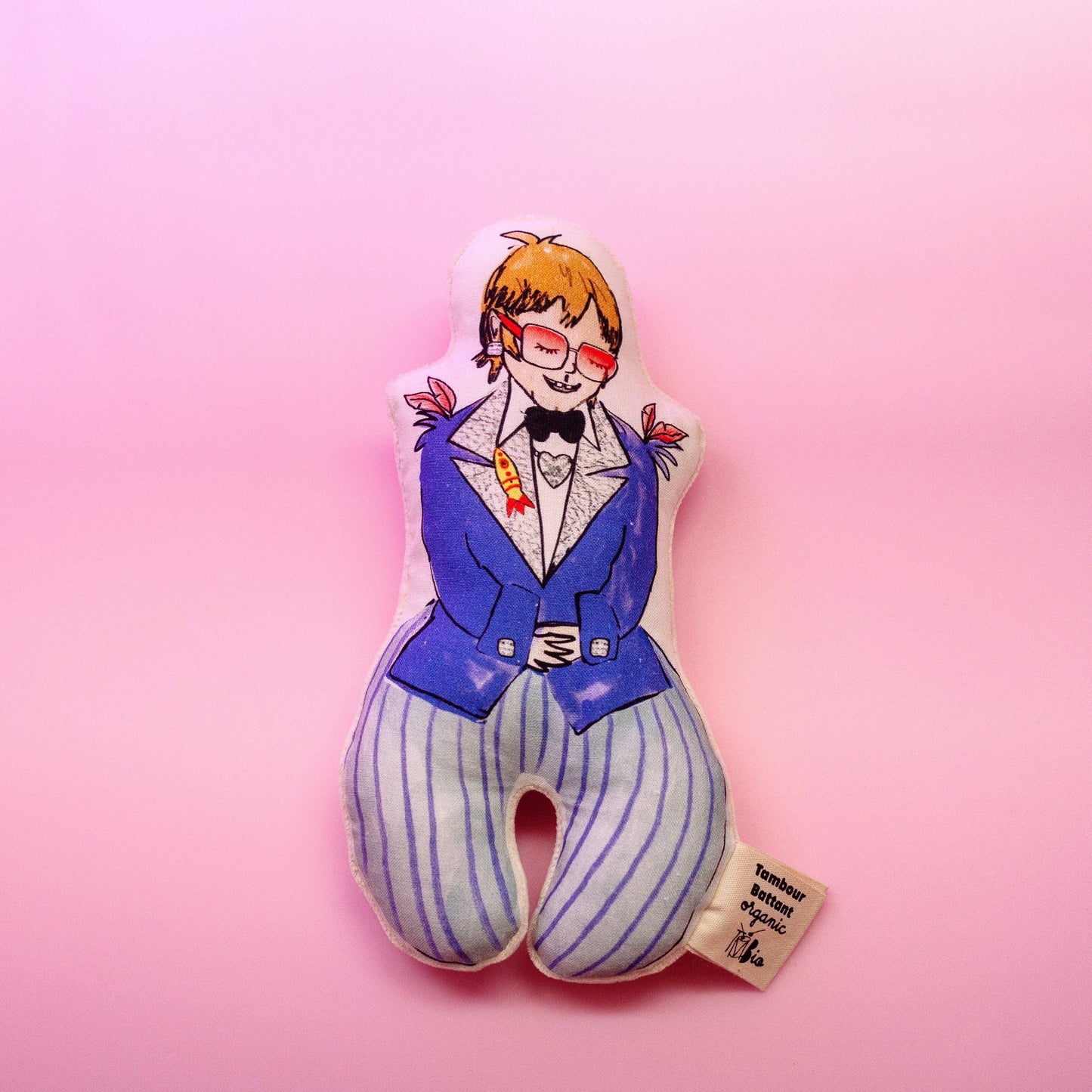 A colorful baby rattle designed as a character wearing a blue suit and glasses, on a pink background.