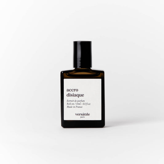 An image of a brown perfume bottle with a black screw on lid on it. The bottle has a square white label on it that says the scent of the perfume 'accro disiaque' along with the amount of perfume in the bottle, that being 15ml and where the perfume was made, that being in France. Beneath this it says versatile Paris.