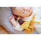 Baby sleeping with a yellow plush toy on a soft surface