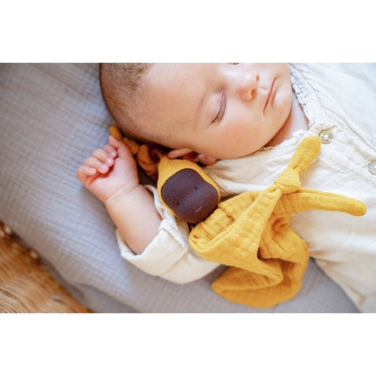 Baby sleeping with a yellow plush toy on a soft surface