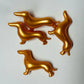 Four gold dog-shaped bath pearls on a white background