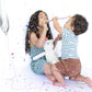 Two children playing with a stuffed animal on a white background with confetti.