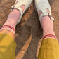 Light blue shoes with pink socks and yellow pants on a dirt ground