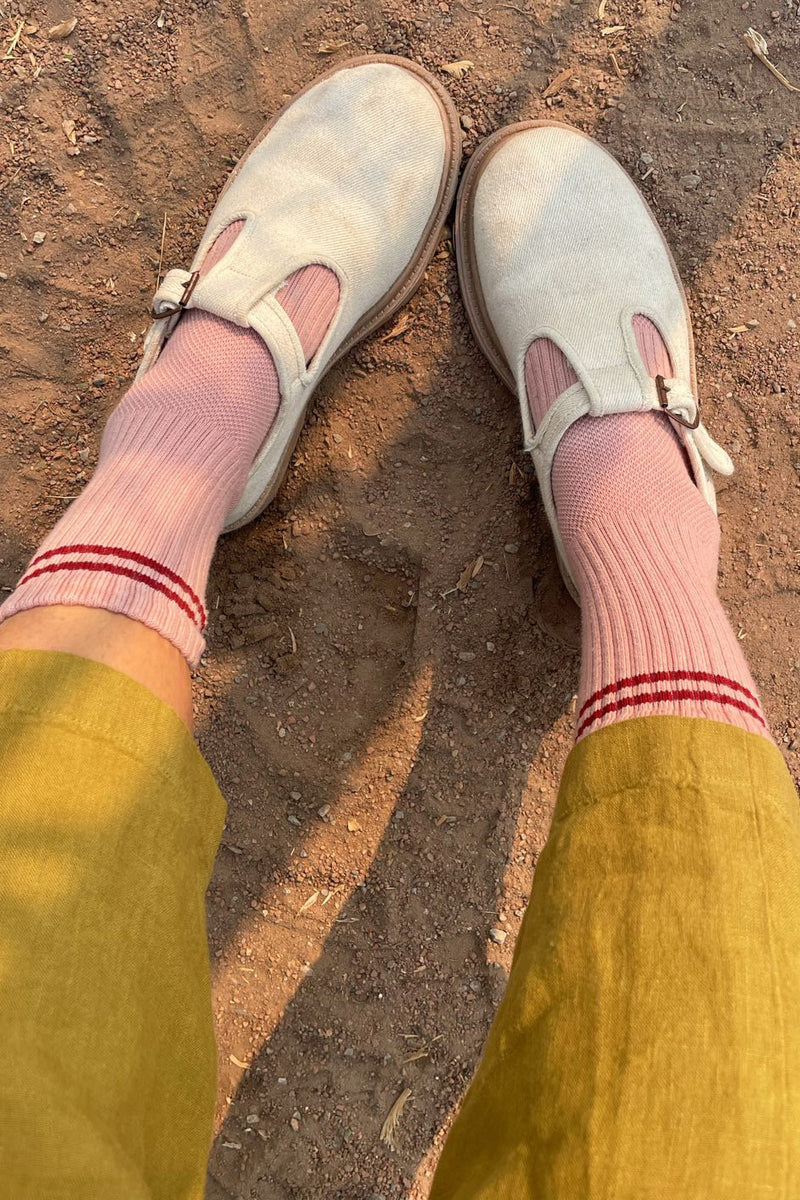 Light blue shoes with pink socks and yellow pants on a dirt ground