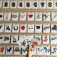 Display of various pins on a wooden shelf with a hand reaching for a pin.