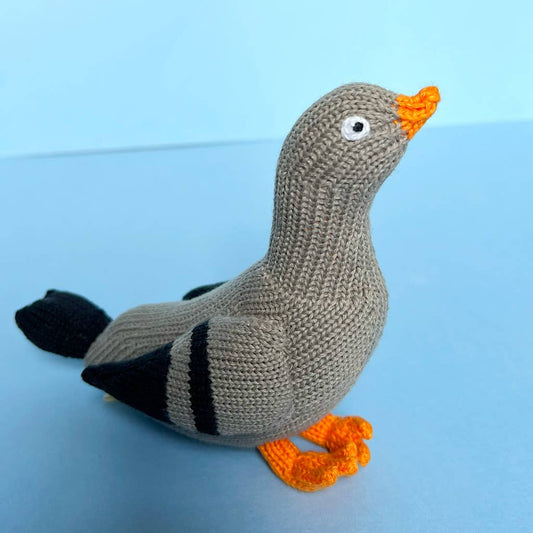 Knitted pigeon toy with orange beak and feet on a blue background