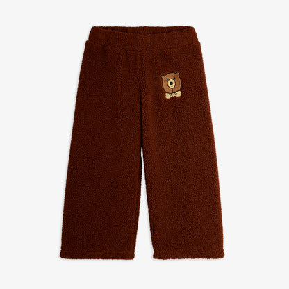 Brown fleece pants with a bear patch on a white background