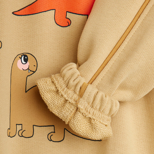 Close-up of beige pants with cartoon dinosaur design on a beige background