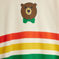 Fabric with a bear face design and colorful stripes on a beige background
