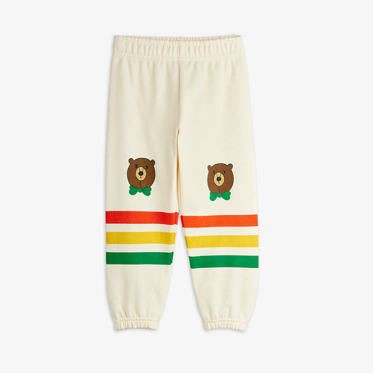 Cream-colored sweatpants with bear illustrations and colorful stripes on a white background
