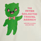 Green alien character with a bow tie and text 'The Inter Galactic Travel Agency' on a white background