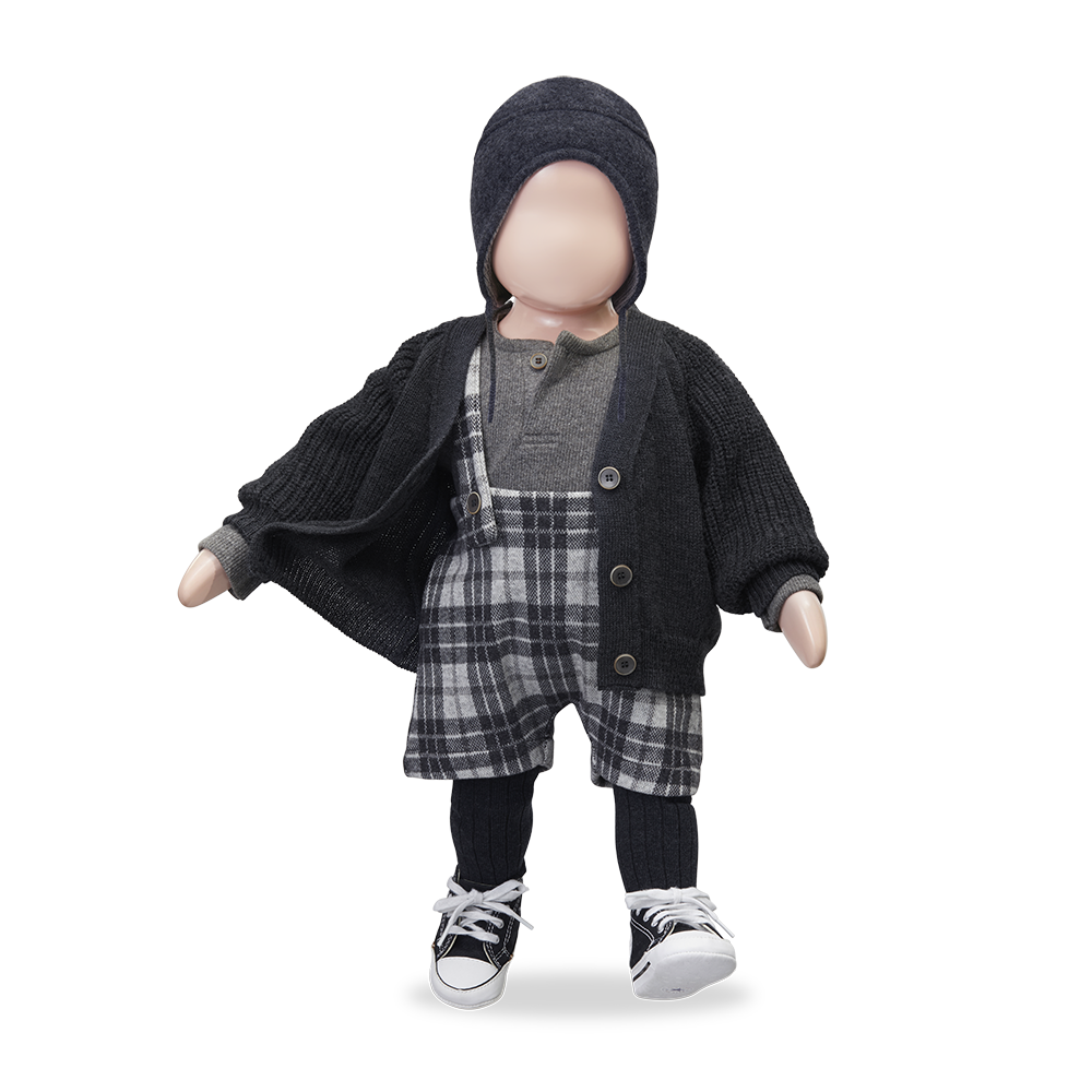 a baby in a grey Henry t-shirt under a nv neck charcoal grey knit cardigan and a pair of short overalls in a large tartan pattern