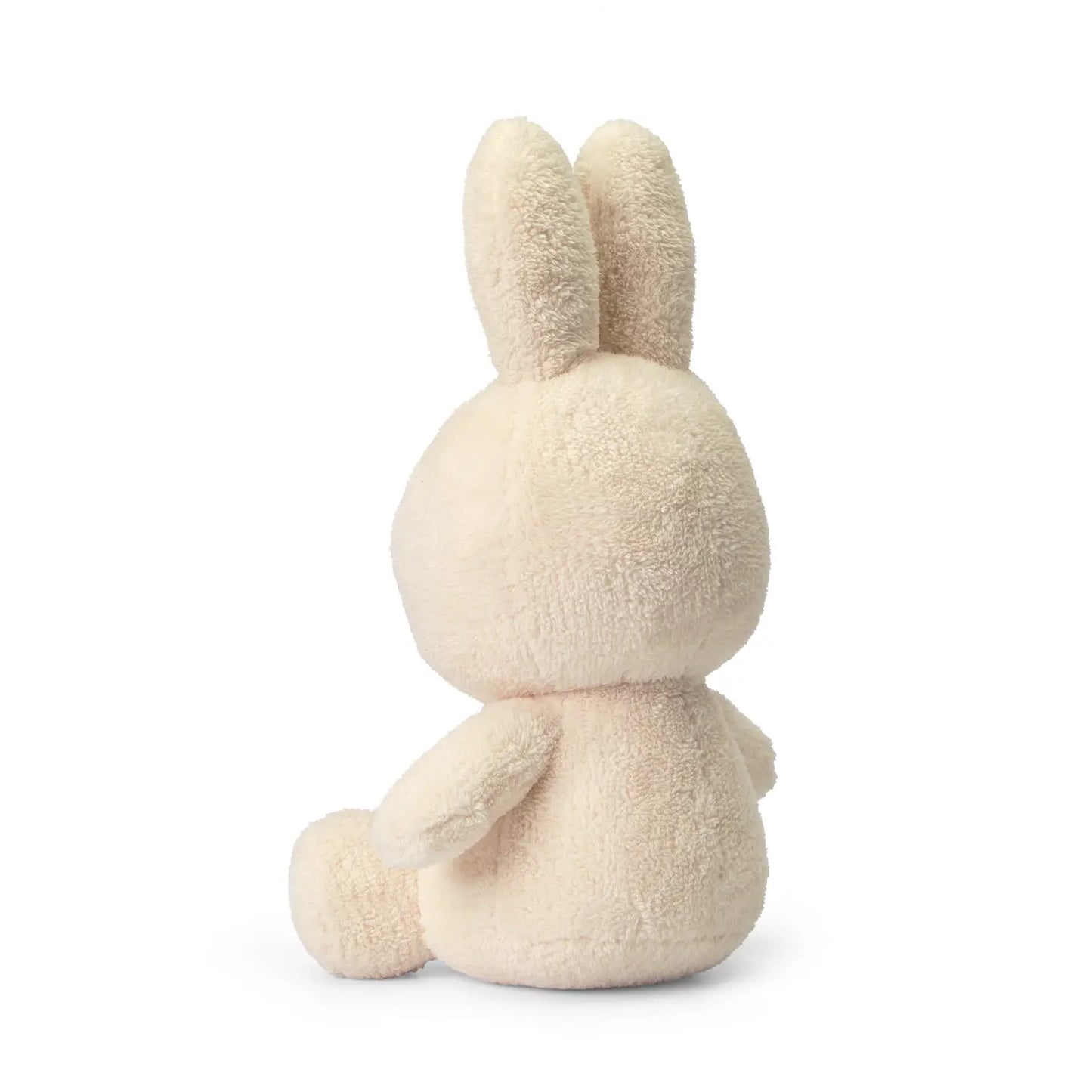 An Miffy Cream terry soft toy in the colour cream. This Miffy has black eyes and nose. It is 33 cm in height. It is made with 100% recycled filling. The background is white. This is the back side of the Miffy. 