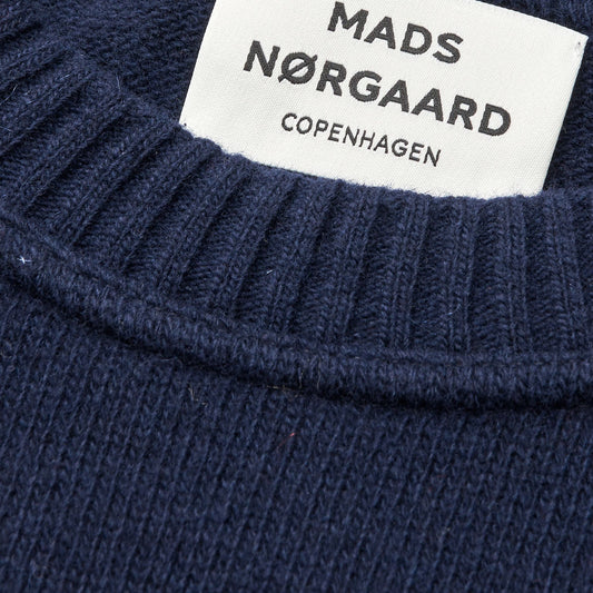 Close-up of a navy sweater with a Mads Nærgaard label.