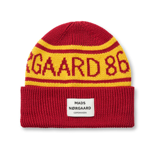 Red and yellow knit beanie with 'Nørgaard 86' text on a white background