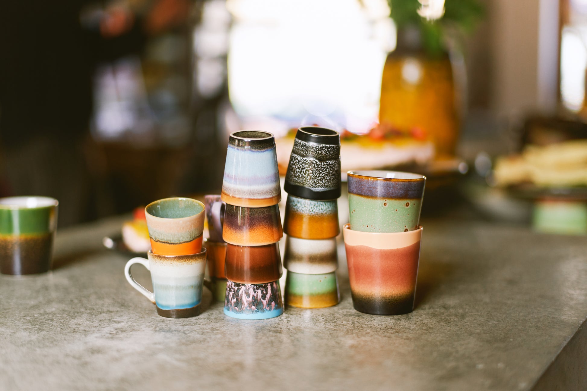 On a marble countertop is a variety of hkliving sets of mugs, the ristretto, espresso and cappuccino mug sticked together