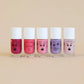 Five bottles of nail polish with cartoon faces on a beige background