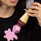 Person wearing a black t-shirt with pink and brown abstract design, holding a pink and brown object.
