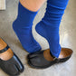 Person wearing blue socks and black open-toe shoes on a neutral background