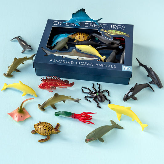 Assorted ocean animal figurines in front of their packaging on a light blue background