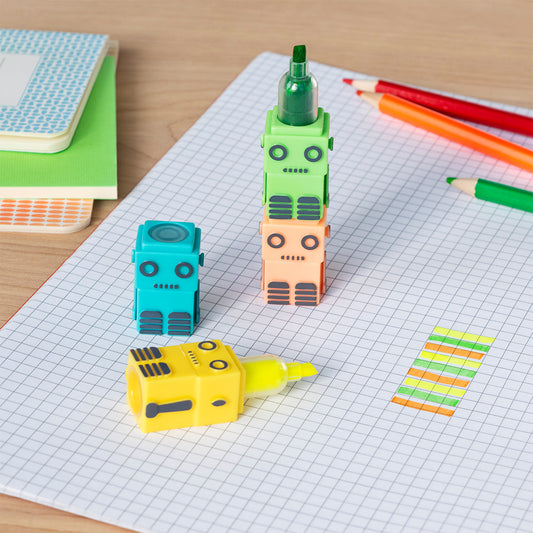Colorful robot-shaped markers on a grid paper with notebooks and pencils in the background.