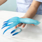 Person holding a blue squid-shaped toy on a white surface