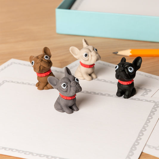 Four small dog figurines with red collars on a piece of paper.