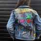 Denim jacket with colorful patches and embroidery on a person against a dark background