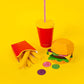 Colorful drink cup with straw, burger, and fries on a yellow background