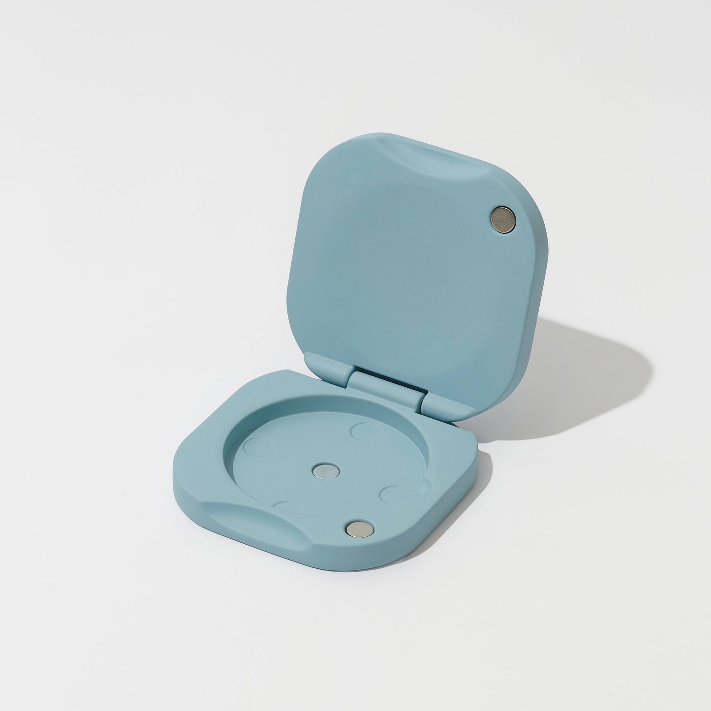 Light blue plastic device with a hinged lid on a white background