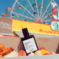 Perfume bottle labeled 'god bless cola' with a carnival background