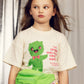 Young girl wearing a t-shirt with a green character and text, holding a green bag.