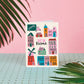 Greeting card with colorful house illustrations on a pink background