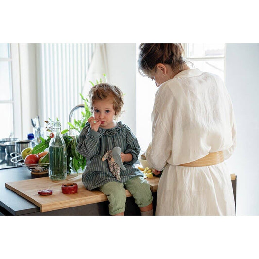 Child sitting on a kitchen counter with an adult standing nearby, surrounded by kitchen items.