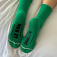 Green socks with text on a white bed sheet
